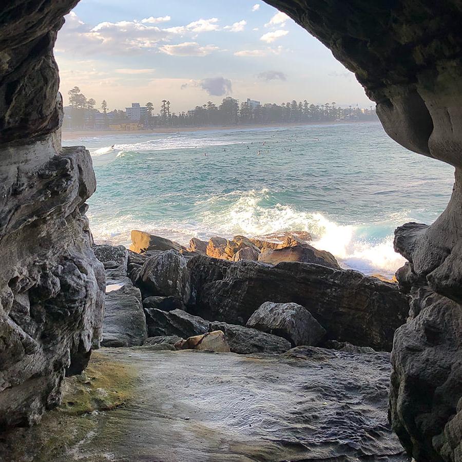 澳大利亚悉尼，从一座以城市为背景的石拱看曼利海滩.
